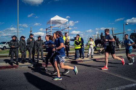 Tel Aviv, Israel, February 27, 2026 Marathon participants run past security forces standing guard along the promenade, showing the high-security environment.のeditorial素材