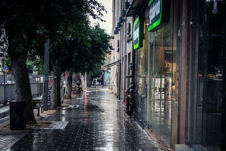 Tel Aviv, Israel, March 21, 2026 Street view of Tel Aviv under the rain with light reflections on the wet pavement and moody urban atmosphere.のeditorial素材