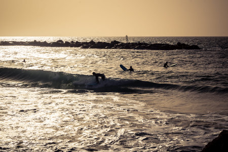 Tel Aviv, Israel, January 25, 2026 Young people surf on the beach in Tel Aviv. This beach remains an...