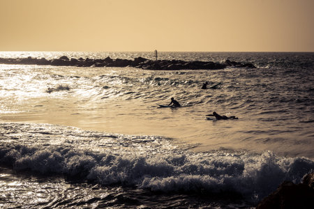 Tel Aviv, Israel, January 25, 2026 Young people surf on the beach in Tel Aviv. This beach remains an...