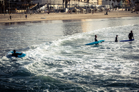 Tel Aviv, Israel, January 25, 2026 Young people surf on the beach in Tel Aviv. This beach remains an...