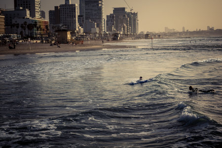 Tel Aviv, Israel, January 25, 2026 Young people surf on the beach in Tel Aviv. This beach remains an...