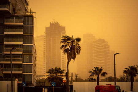 Tel Aviv, Israel, March 14, 2026 A thick layer of desert sand and dust blankets the streets during a Sharav atmospheric phenomenon, creating a surreal orange glow and reducing visibility across the metropolitan area.のeditorial素材