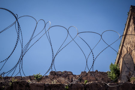 Hebron, West Bank, Palestine, March 28, 2026 Razor wire, metal fencing, and military barriers are...