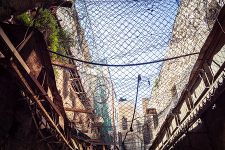 Hebron, West Bank, Palestine, March 28, 2026 Metal nets and fencing are stretched high above the...