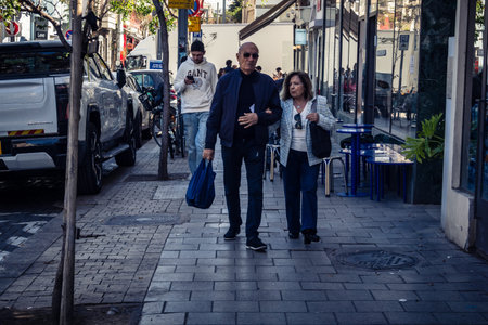 Tel Aviv, Israel, February 26 2026, Pedestrians walking on Sheinkin Street, lively urban scene with dynamic movement, Bauhaus architecture as backdrop, vibrant city life, sunlight on diverse street textures, rhythmic geometry and cascading light observed のeditorial素材