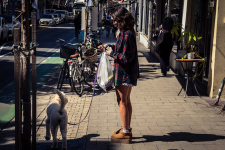 Tel Aviv, Israel, February 26 2026, Pedestrians walking on Sheinkin Street, lively urban scene with dynamic movement, Bauhaus architecture as backdrop, vibrant city life, sunlight on diverse street textures, rhythmic geometry and cascading light observed のeditorial素材