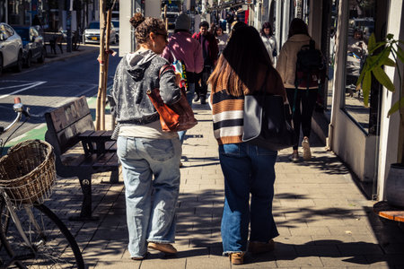 Tel Aviv, Israel, February 26 2026, Pedestrians walking on Sheinkin Street, lively urban scene with dynamic movement, Bauhaus architecture as backdrop, vibrant city life, sunlight on diverse street textures, rhythmic geometry and cascading light observed のeditorial素材