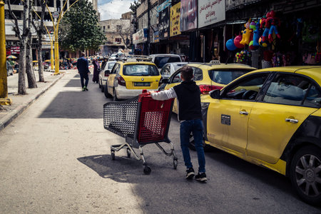 Hebron, West Bank, Palestine, March 31, 2026 Palestinian children are seen pushing metal shopping...
