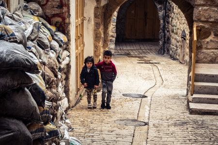Hebron, West Bank, Palestine, April 01, 2026 Two young Palestinian boys are walking along a narrow,...