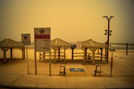 Tel Aviv, Israel, March 14, 2026 Empty playgrounds and beach structures stand abandoned as a thick shroud of desert dust engulfs the Mediterranean coastline, creating a surreal monochromatic landscape and extreme atmospheric conditions during a Sharav eveのeditorial素材