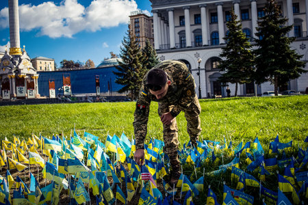 Kyiv, Ukraine, October 12, 20223 soldiers of the foreign legion in Ukraine, of American, Canadian and Belgian nationality pay homage to one of their killed in action in Kherson during the fights with the Russian army. A small flag with the name of the deaのeditorial素材