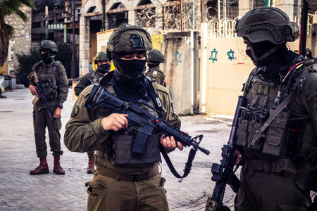 Hebron, Palestinian Territory, February 7, 2026 Israeli soldiers (IDF) in tactical gear provide security and escort a group of Jewish settlers through the streets of the Old City, in H2 divided area.