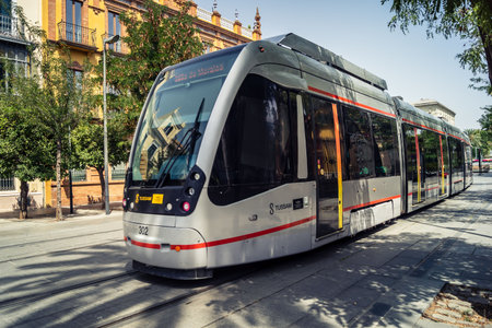 Seville, Andalusia, Spain. July 30, 2026 Modern Metrocentro tramway moves along Avenida de la ConstituciÃ³n in the historic city center during a hot summer afternoon. The scene highlights daily urban public transit and electric mobility connecting major c