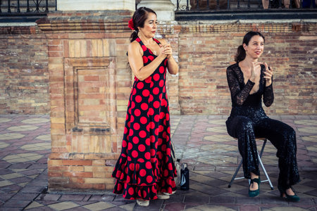 Seville, Andalusia, Spain, August 11, 2026. Flamenco dancers perform alongside a guitarist, singer, and hand clapper under the tiled alcoves of the Place of Spain in Seville. Street performers showcase traditional Andalusian art, music, and dance to gathe
