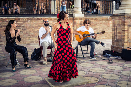 Seville, Andalusia, Spain, August 11, 2026. Flamenco dancers perform alongside a guitarist, singer, and hand clapper under the tiled alcoves of the Place of Spain in Seville. Street performers showcase traditional Andalusian art, music, and dance to gathe