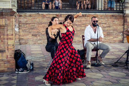 Seville, Andalusia, Spain, August 11, 2026. Flamenco dancers perform alongside a guitarist, singer, and hand clapper under the tiled alcoves of the Place of Spain in Seville. Street performers showcase traditional Andalusian art, music, and dance to gathe