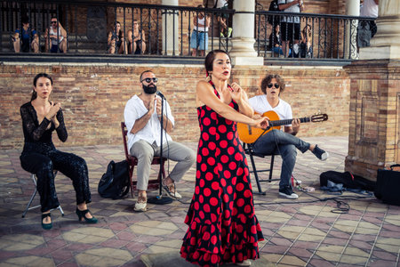 Seville, Andalusia, Spain, August 11, 2026. Flamenco dancers perform alongside a guitarist, singer, and hand clapper under the tiled alcoves of the Place of Spain in Seville. Street performers showcase traditional Andalusian art, music, and dance to gathe