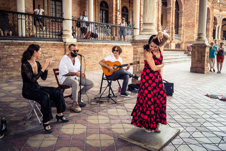 Seville, Andalusia, Spain, August 11, 2026. Flamenco dancers perform alongside a guitarist, singer, and hand clapper under the tiled alcoves of the Place of Spain in Seville. Street performers showcase traditional Andalusian art, music, and dance to gathe