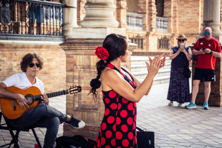 Seville, Andalusia, Spain, August 11, 2026. Flamenco dancers perform alongside a guitarist, singer, and hand clapper under the tiled alcoves of the Place of Spain in Seville. Street performers showcase traditional Andalusian art, music, and dance to gathe