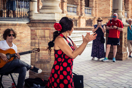 Seville, Andalusia, Spain, August 11, 2026. Flamenco dancers perform alongside a guitarist, singer, and hand clapper under the tiled alcoves of the Place of Spain in Seville. Street performers showcase traditional Andalusian art, music, and dance to gathe
