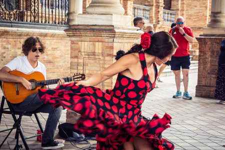 Seville, Andalusia, Spain, August 11, 2026. Flamenco dancers perform alongside a guitarist, singer, and hand clapper under the tiled alcoves of the Place of Spain in Seville. Street performers showcase traditional Andalusian art, music, and dance to gathe