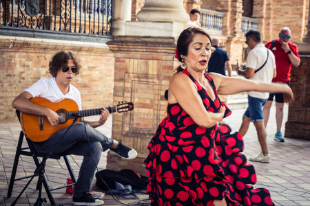 Seville, Andalusia, Spain, August 11, 2026. Flamenco dancers perform alongside a guitarist, singer, and hand clapper under the tiled alcoves of the Place of Spain in Seville. Street performers showcase traditional Andalusian art, music, and dance to gathe