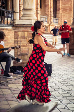 Seville, Andalusia, Spain, August 11, 2026. Flamenco dancers perform alongside a guitarist, singer, and hand clapper under the tiled alcoves of the Place of Spain in Seville. Street performers showcase traditional Andalusian art, music, and dance to gathe