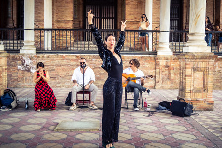 Seville, Andalusia, Spain, August 11, 2026. Flamenco dancers perform alongside a guitarist, singer, and hand clapper under the tiled alcoves of the Place of Spain in Seville. Street performers showcase traditional Andalusian art, music, and dance to gathe