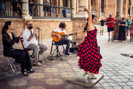 Seville, Andalusia, Spain, August 11, 2026. Flamenco dancers perform alongside a guitarist, singer, and hand clapper under the tiled alcoves of the Place of Spain in Seville. Street performers showcase traditional Andalusian art, music, and dance to gathe