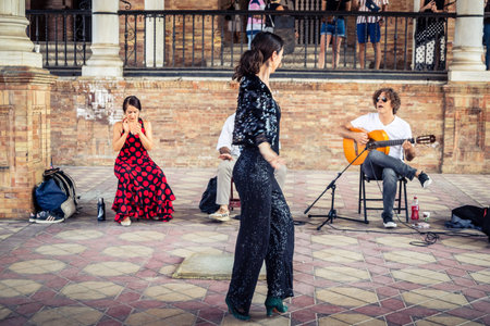 Seville, Andalusia, Spain, August 11, 2026. Flamenco dancers perform alongside a guitarist, singer, and hand clapper under the tiled alcoves of the Place of Spain in Seville. Street performers showcase traditional Andalusian art, music, and dance to gathe