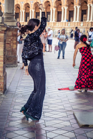 Seville, Andalusia, Spain, August 11, 2026. Flamenco dancers perform alongside a guitarist, singer, and hand clapper under the tiled alcoves of the Place of Spain in Seville. Street performers showcase traditional Andalusian art, music, and dance to gathe