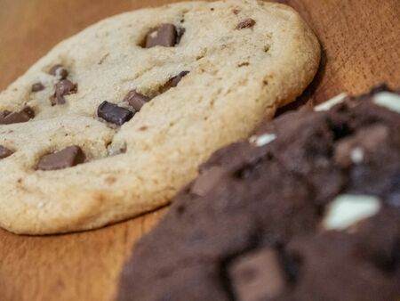 Regular and chocolate homemade cookies. They are on a wooden background