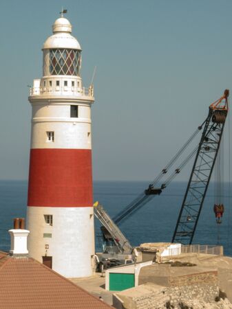Some construction vehicles next to a lighthouse. It's a sunny day of summer.の写真素材