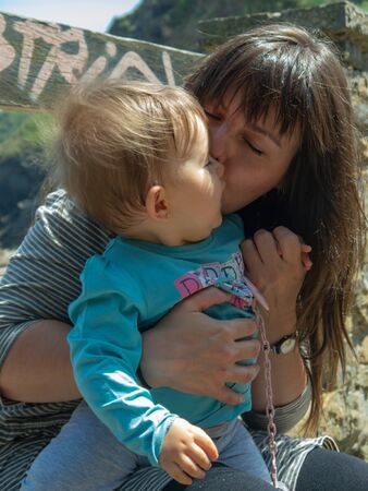 Mother holding her little daughter. They are happy and smiling on a sunny day.の写真素材