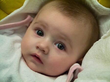 Cute little caucasian baby. She is lying on her stroller, watching.