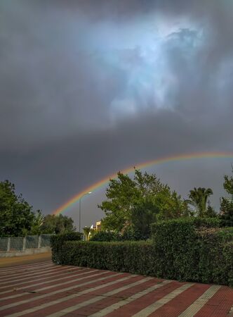Fully colored rainbow. It is above the city on a cloudy day.の写真素材