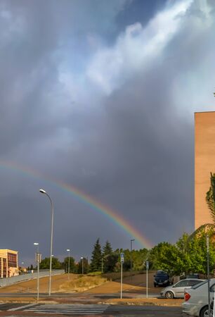 Fully colored rainbow. It is above the city on a cloudy day.の写真素材