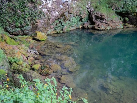 Little quiet pond. It is surrounded by rocks and vegetation.の写真素材