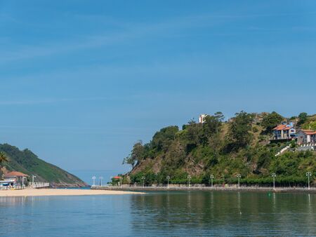 Village next to the sea, with a little empty beach. It is surrounded by nature, and it is a sunny day with a blue sky.の写真素材