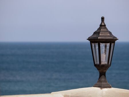 Vintage lamp light close up. It is next to the sea, which can be seen as a blurry background.の写真素材