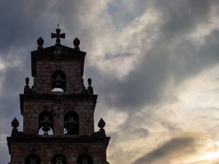 Dark bell tower. Its silhouette can be clearly appreciated contrasting with a cloudy sky.の写真素材
