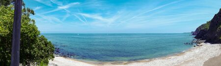 Panoramic landscape. There is an empty beach, and you can see the ocean and the horizon far away.の写真素材