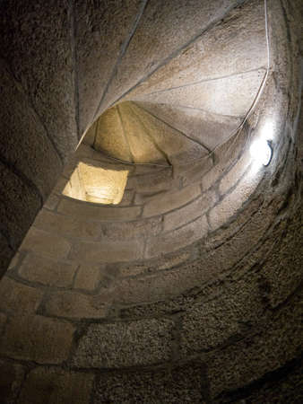 Detail of the wall of a spiral staircase with a loophole and an artificial light inside the Guarda...