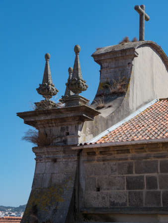 Detailed view of the roof of a church in Porto, on whose pediment there is a cross and several spires, which give shade to a seagullの写真素材