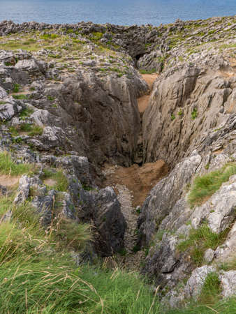 Cliffs full of rocks and vegetation by the sea in Los Bufones de LLanes, in Cantabria, Spainの写真素材