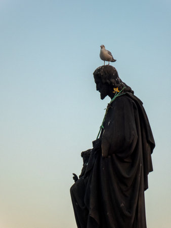 Silhouette of a statue of Christ surrounded by doves on the Charles Bridge in Pragueの写真素材