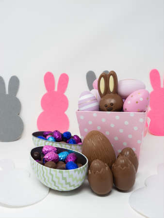 Set of Easter chocolates, with a bunny and chocolate eggs, on a white background with bunny silhouettes.の写真素材