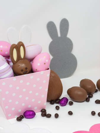 Set of Easter chocolates, with a bunny and chocolate eggs, on a white background with bunny silhouettes.の写真素材