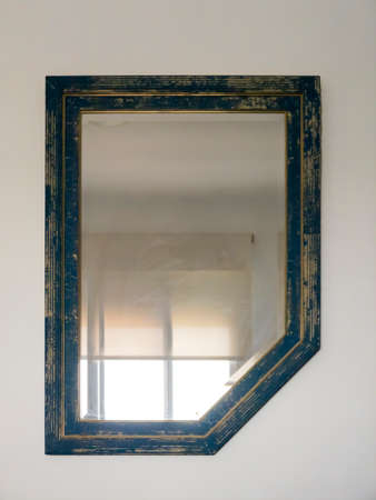 Antique and worn mirror hanging on a white wallの写真素材
